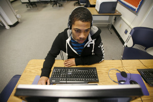Student working on a computer using headphones