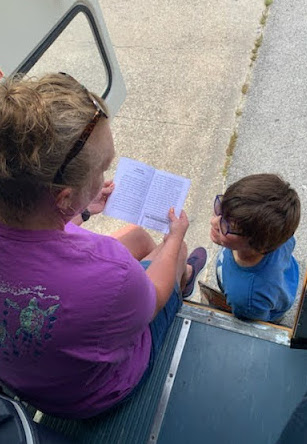 Boy being reading to on the back of a school bus