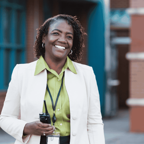A photo of a female principal standing outside of a school.